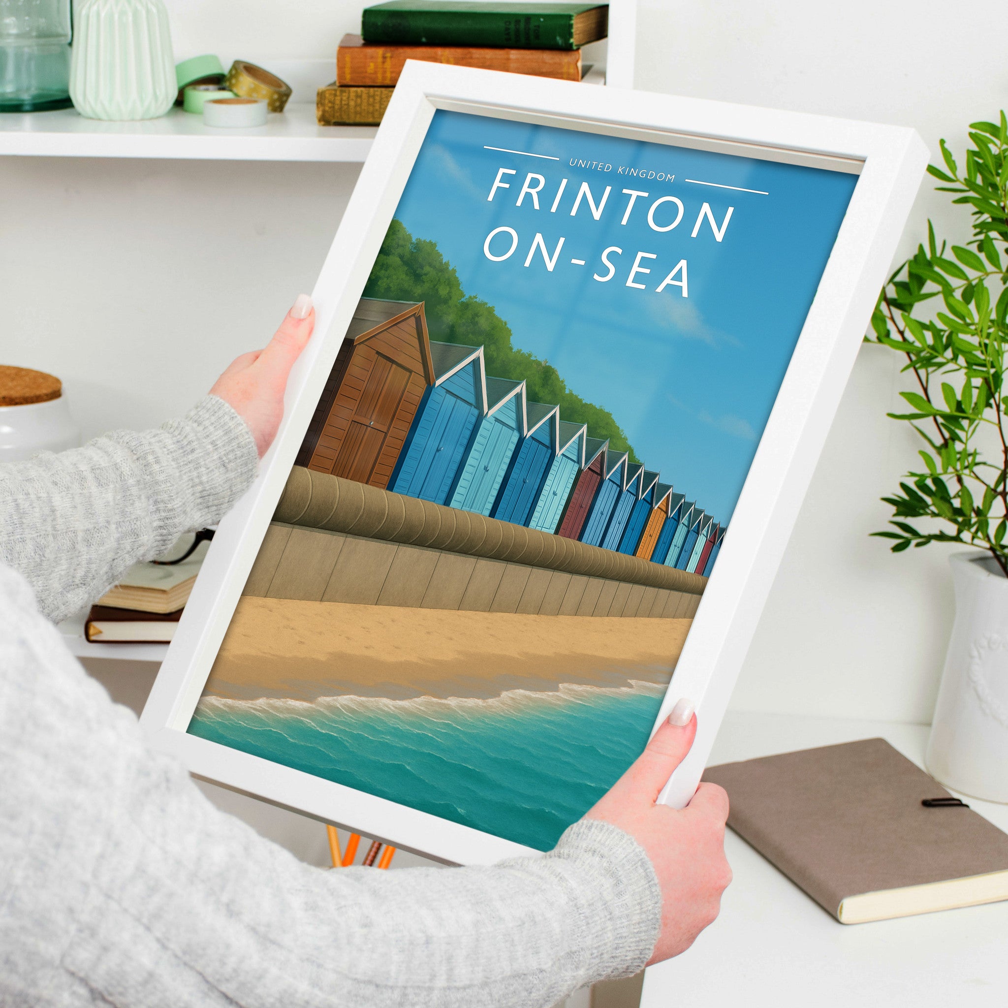 Frinton-on-Sea Travel Poster in a white frame, held to show scale
