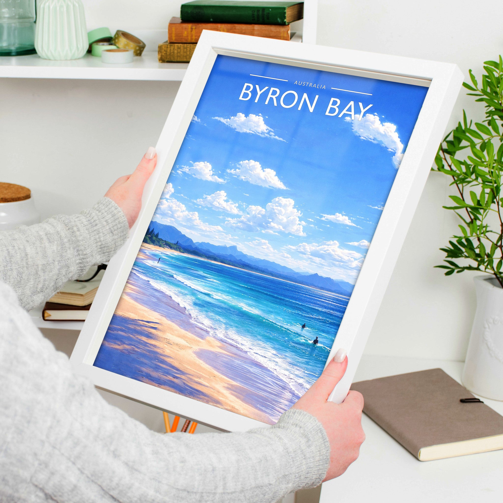 Byron Bay Travel Poster in a white frame, held to show scale