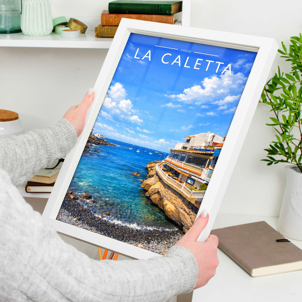 La Caletta Travel Poster in a white frame, held to show scale