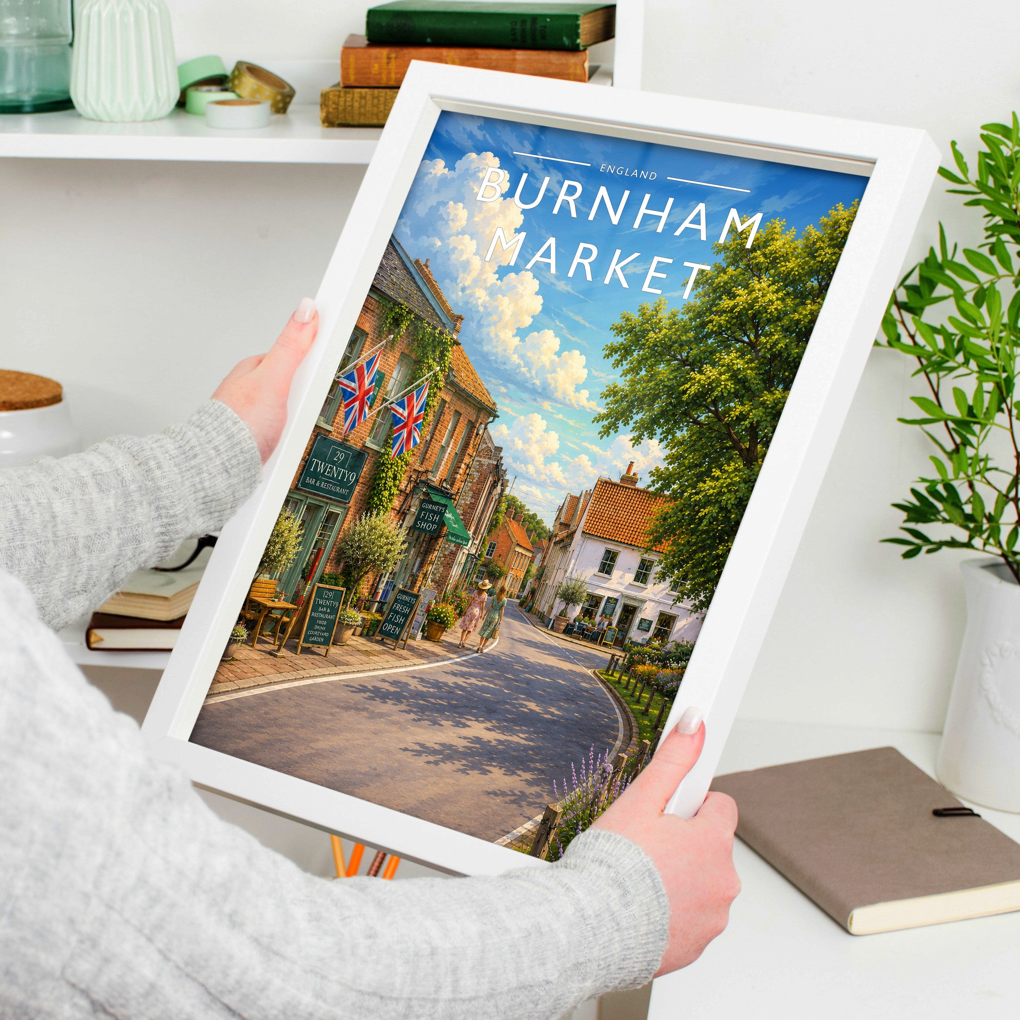 Burnham Market #4 Travel Poster in a white frame, held to show scale